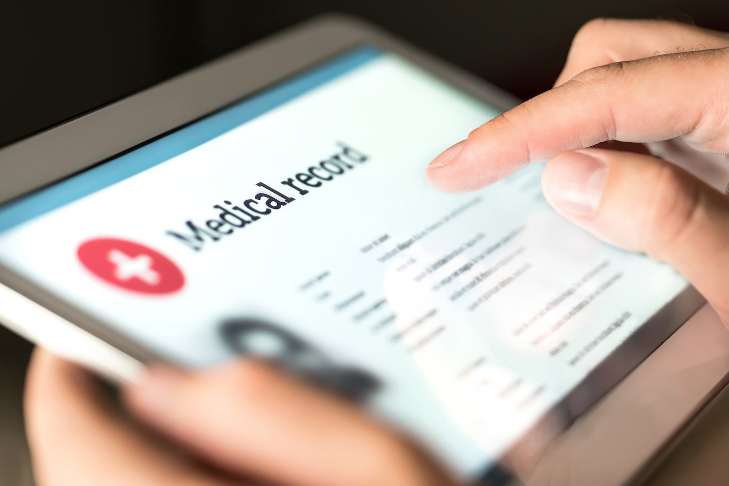 Doctor uses tablet to access an electronic medical record with a patient's health information.